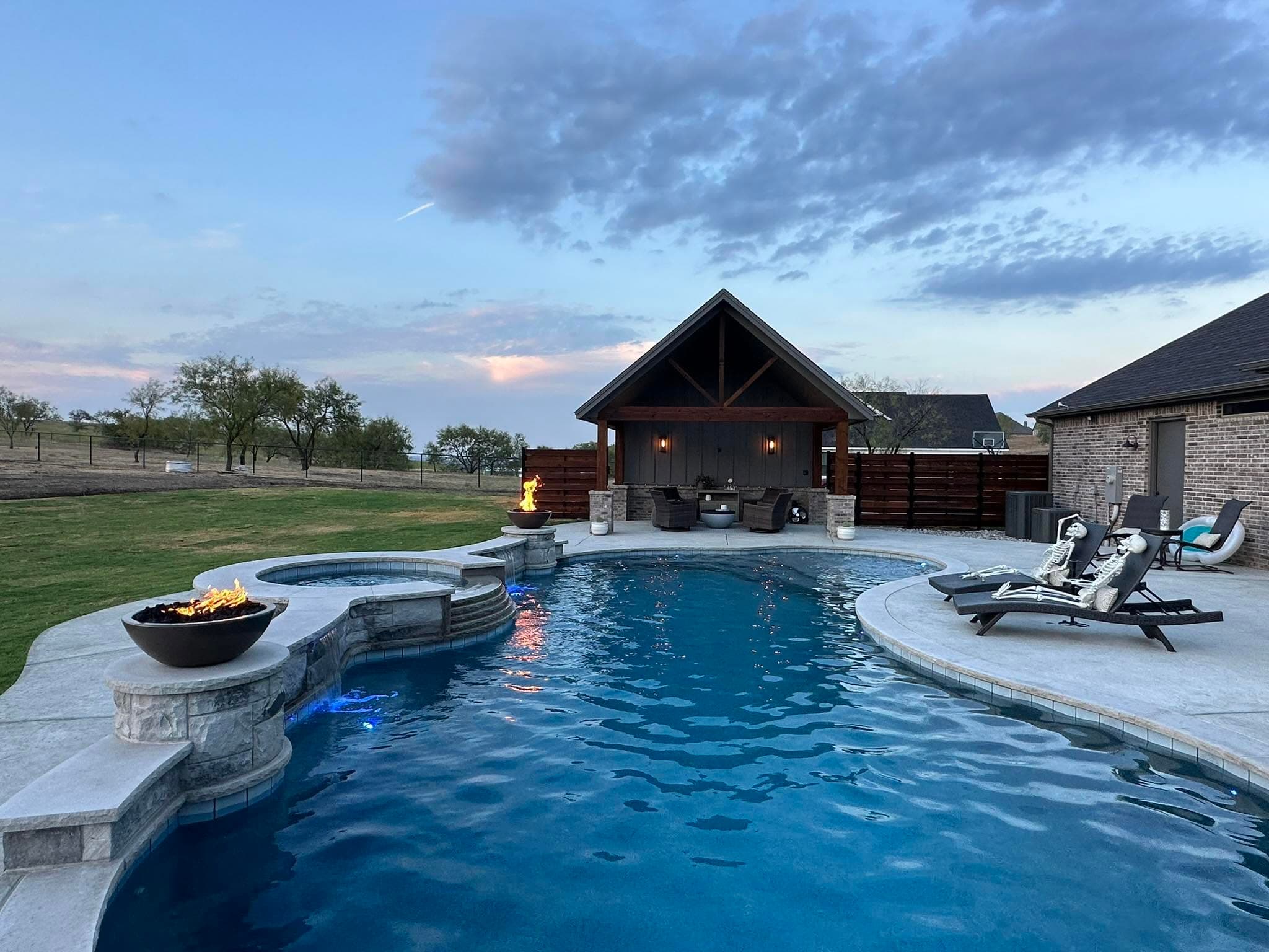 Custom pool, raised spa, fire feature, and pavilion at dusk
