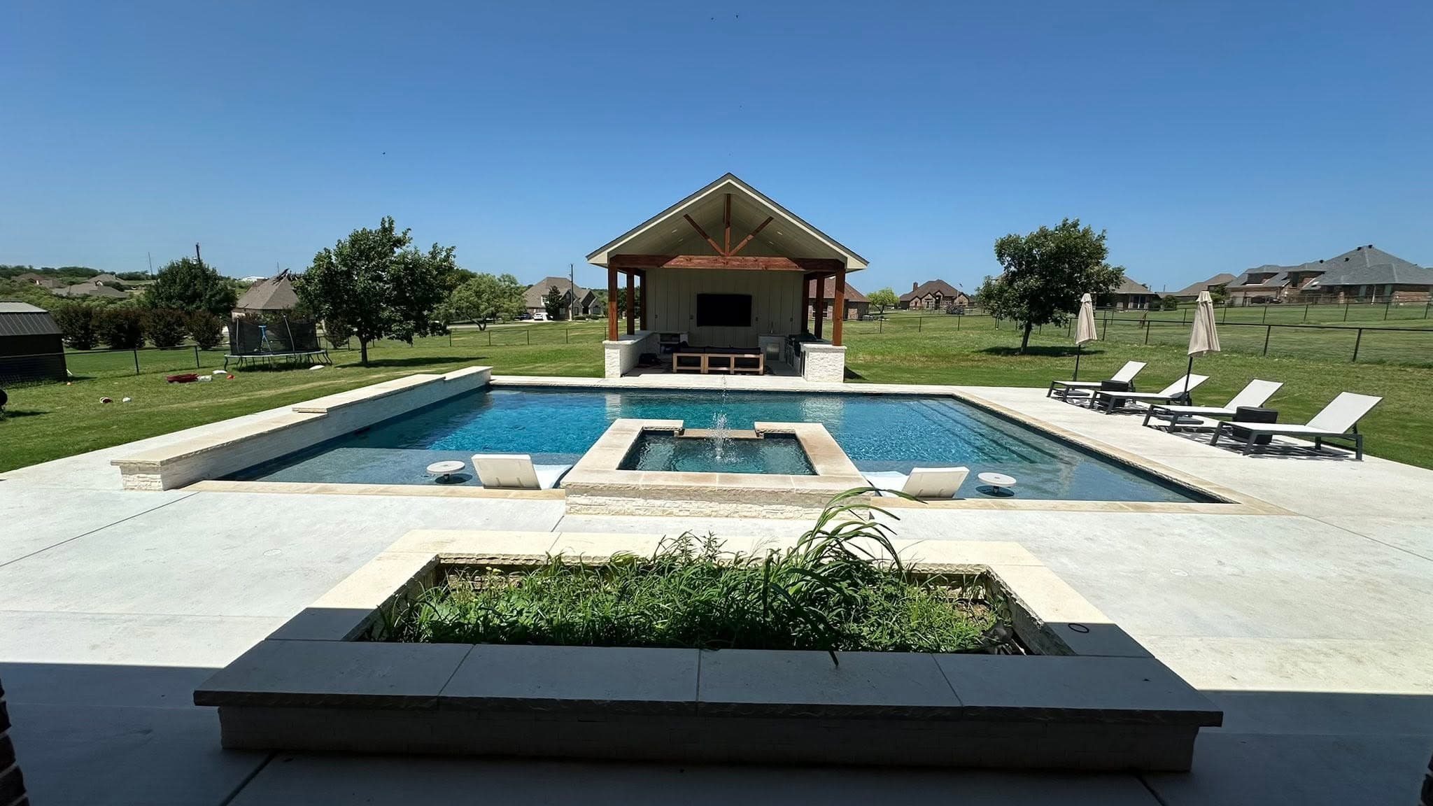 Pool, raised spa, pavilion, and lawn in a completed backyard